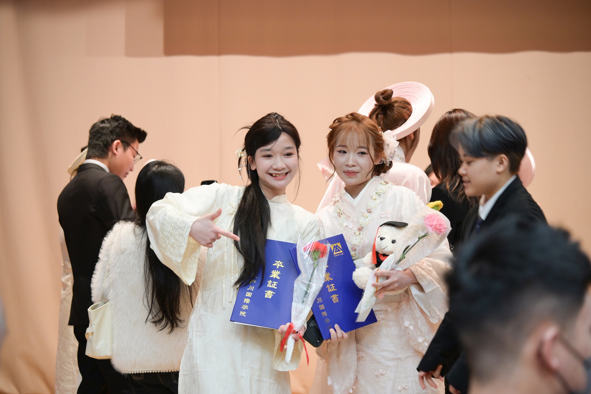 卒業証書を見せ合う学生